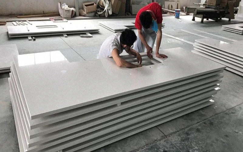 Workers inspecting custom cut-to-size white quartz countertops in a factory, ready for apartment and hospitality projects