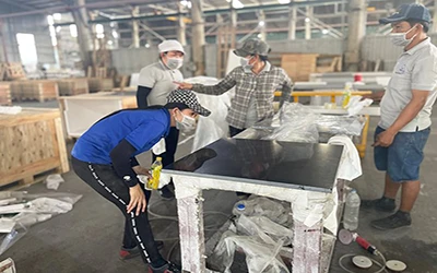 Quality control worker inspecting finished quartz countertop for defects before packing