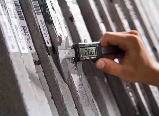 Factory worker using digital caliper for quartz slab thickness measurement before shipment